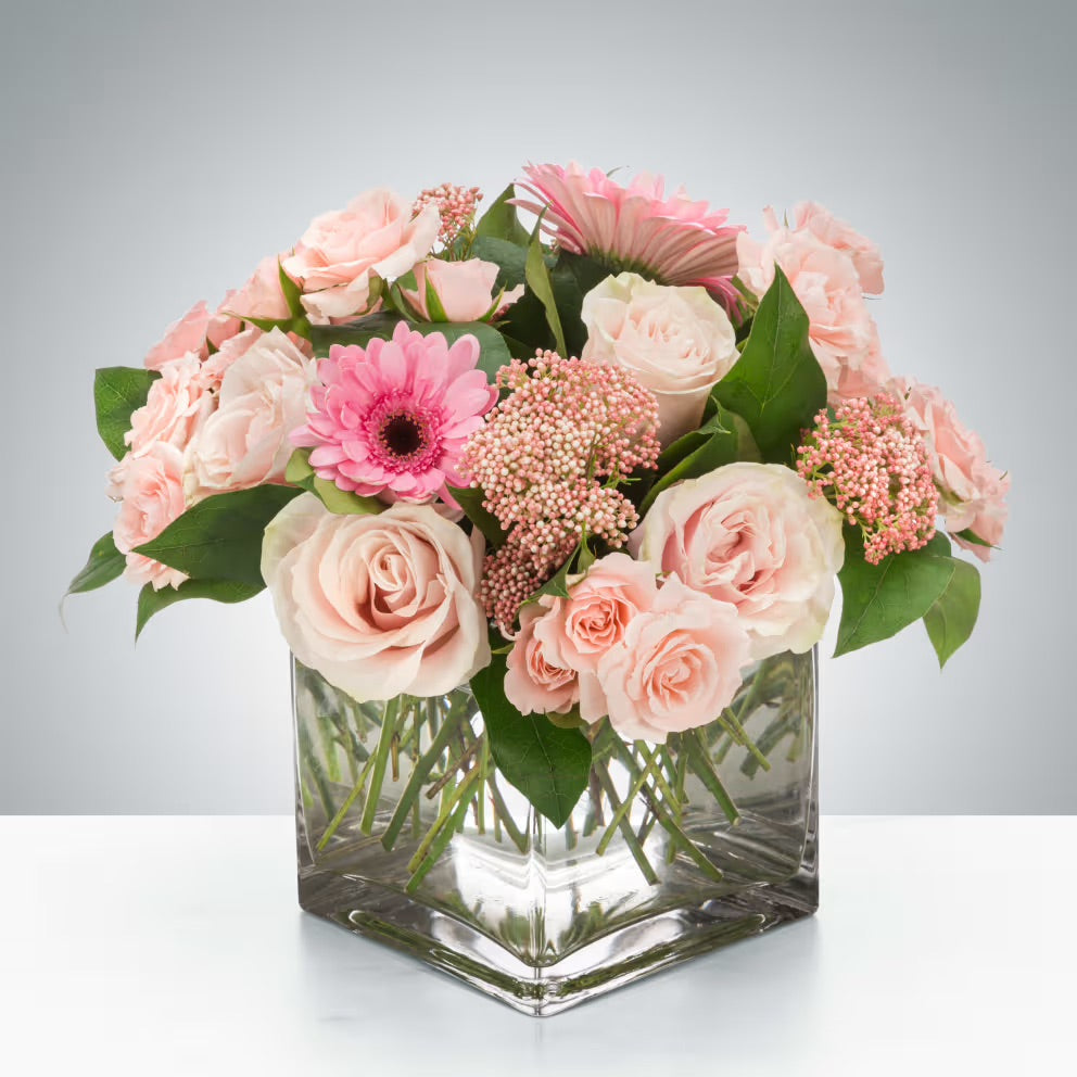 A delicate pastel pink floral arrangement with soft, romantic blooms.